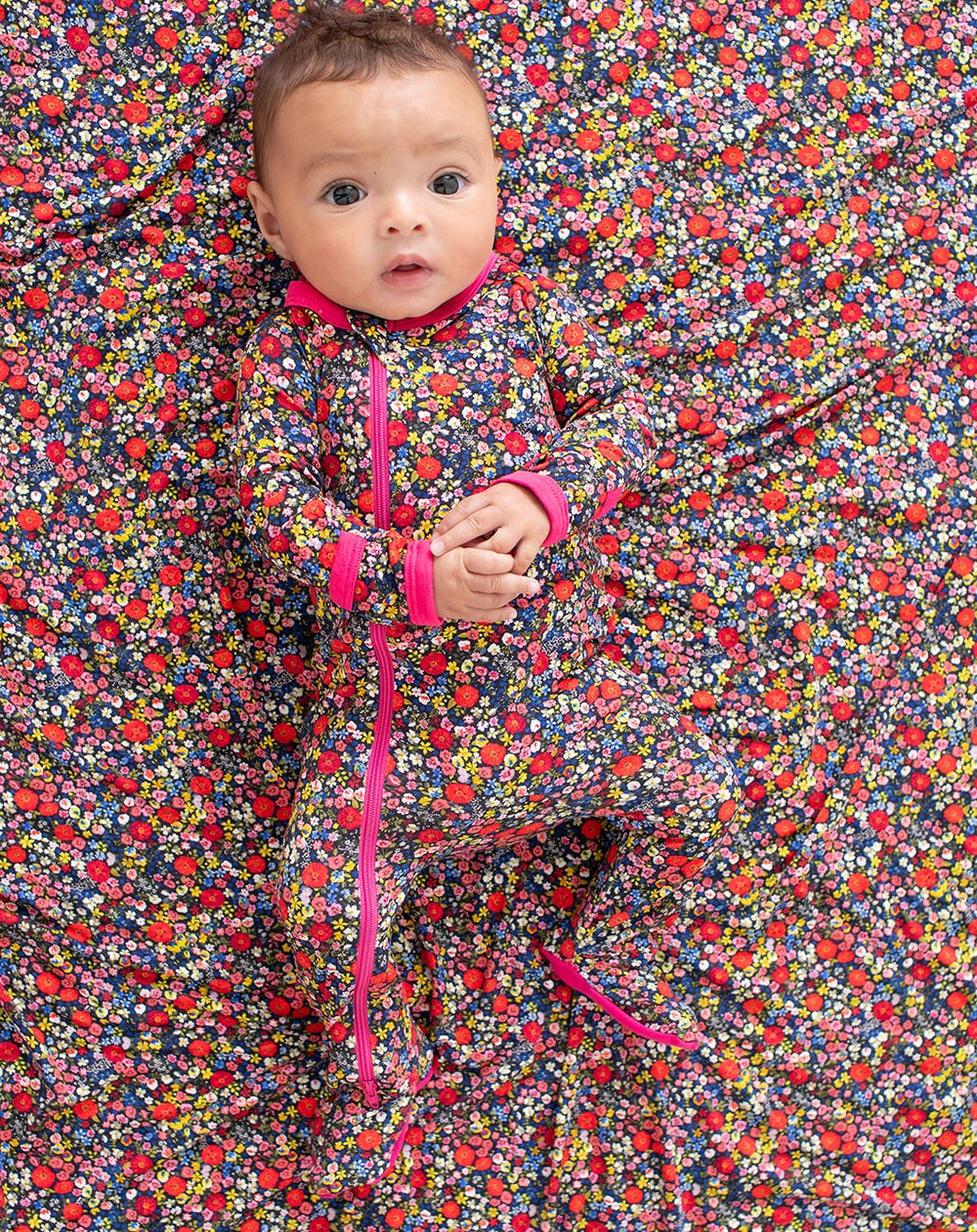 Baby in a floral onesie lying on a colorful floral fabric background