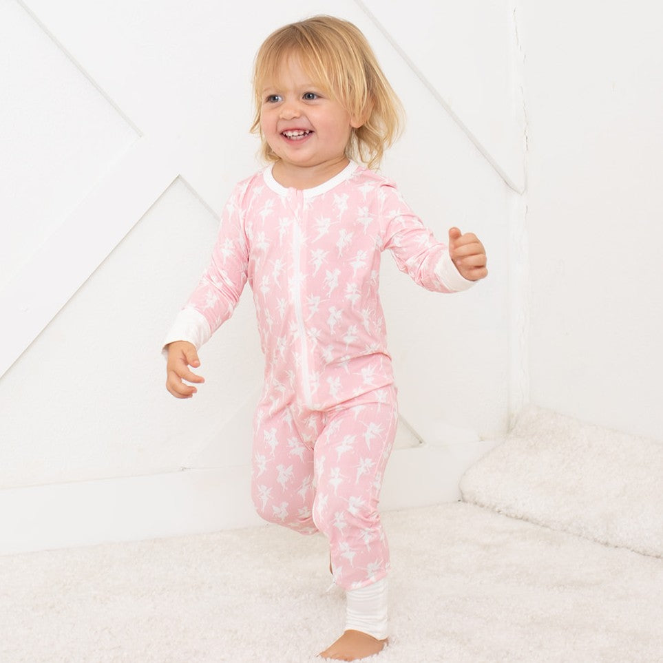 Child wearing a pink onesie with white patterns on a white background