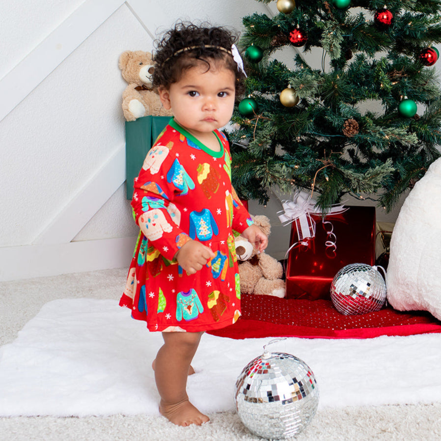 Child in festive pajamas with a Christmas tree and decorations in the background