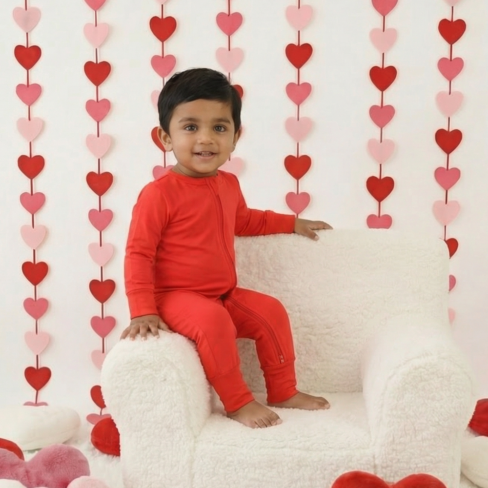 Child in red outfit sitting on a white chair surrounded by heart decorations
