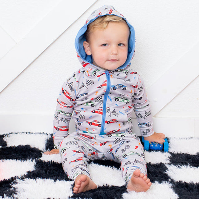 Child in a colorful onesie sitting between two traffic cones on a checkered floor.