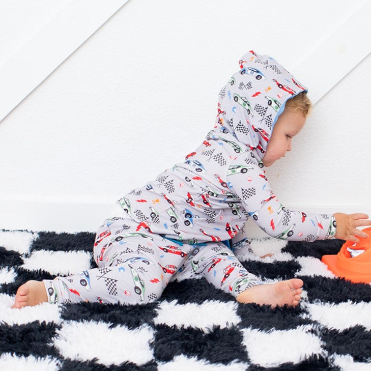 Child wearing a patterned onesie sitting on a checkered blanket