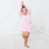 Child wearing a pink dress with white polka dots on a white background