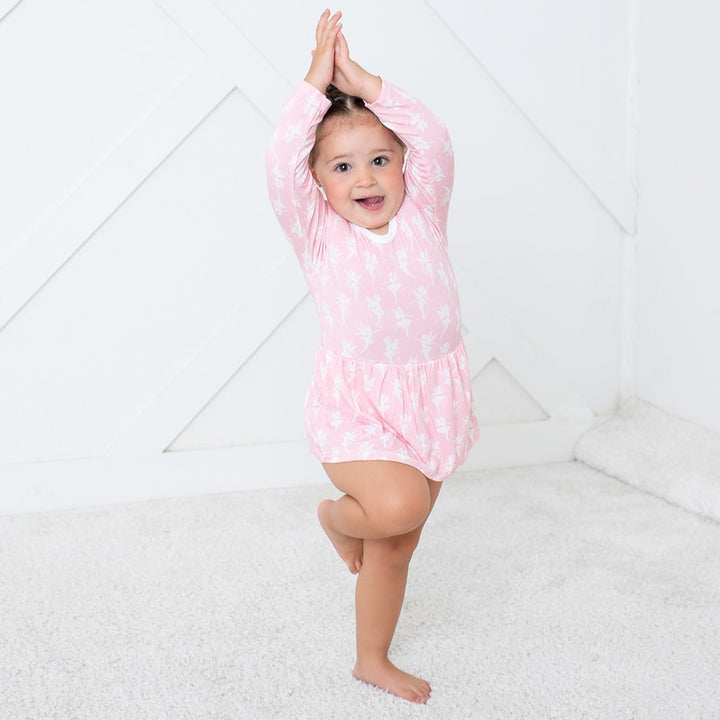 Child wearing a pink dress with white polka dots on a white background