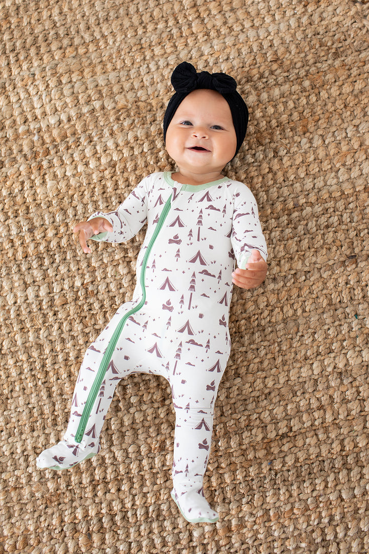 Baby wearing a patterned onesie on a textured brown surface