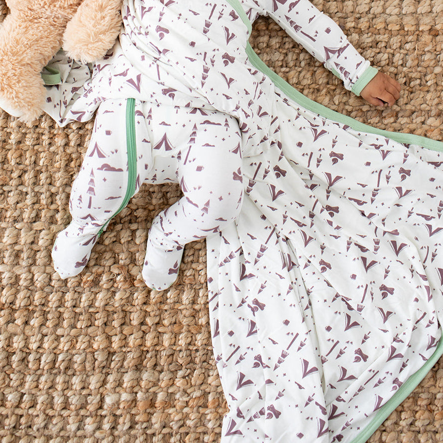 Baby lying on a textured surface with teddy bears and a blanket