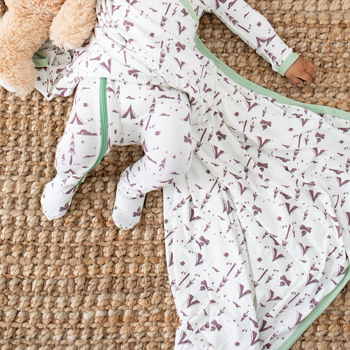 Baby lying on a textured surface with teddy bears and a blanket