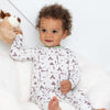 Baby wearing a white onesie with brown animal prints, holding a plush toy on a white background