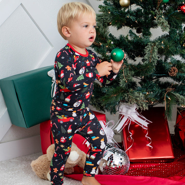 Child in pajamas near a decorated Christmas tree with presents underneath.