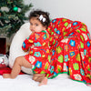Child in a festive setting with Christmas tree, presents, and decorations.