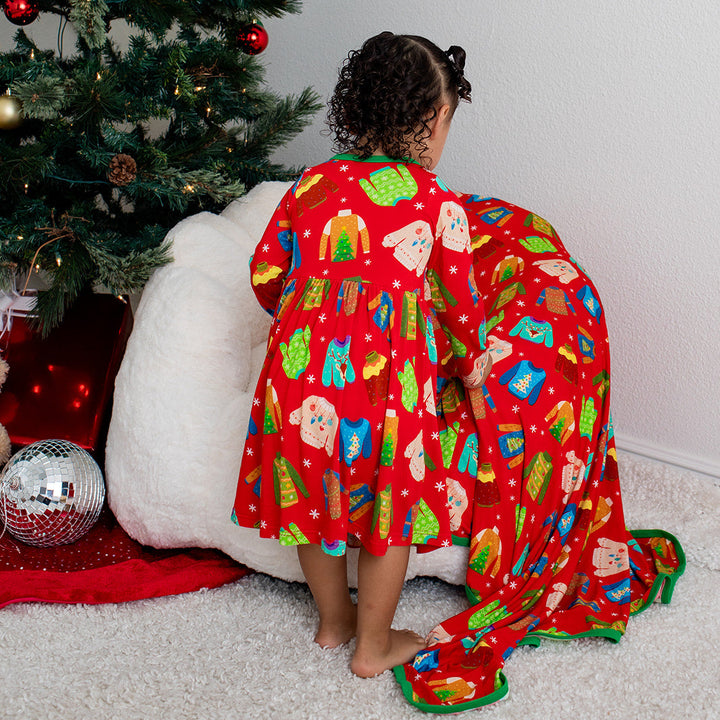 Child in a red pajama with Christmas tree decorations