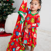 Child wearing a red holiday-themed dress with a Christmas tree in the background
