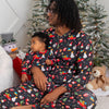 Woman and child wearing matching Christmas-themed pajamas in front of a decorated Christmas tree.