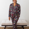 Woman wearing a colorful pajama set sitting on a bench against a white wall.