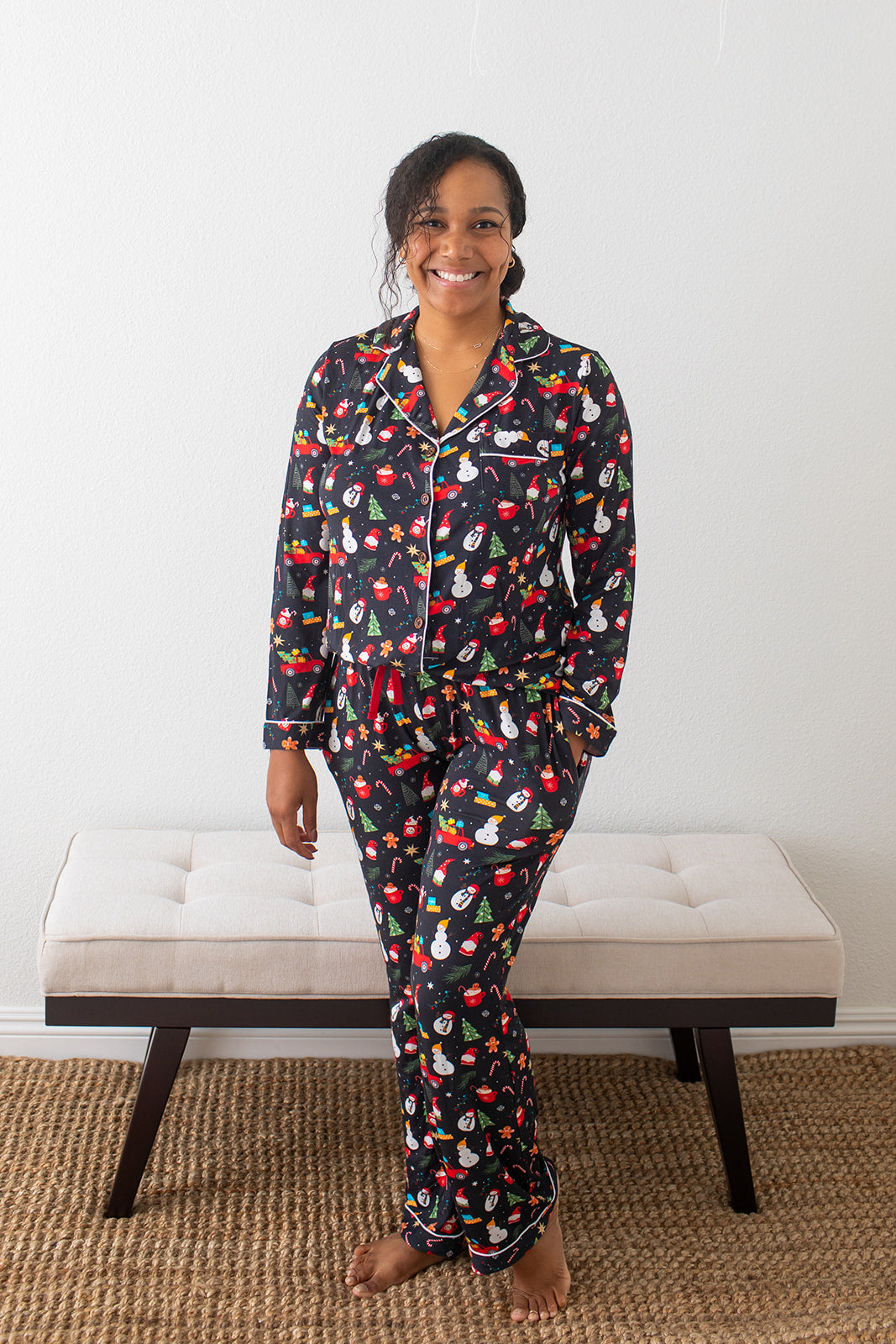 Woman wearing a colorful pajama set sitting on a bench against a white wall.