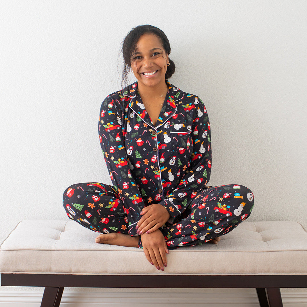 Woman wearing a colorful pajama set sitting on a bench against a white wall