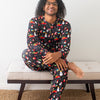 Man wearing colorful pajamas sitting on a bench with a white wall background