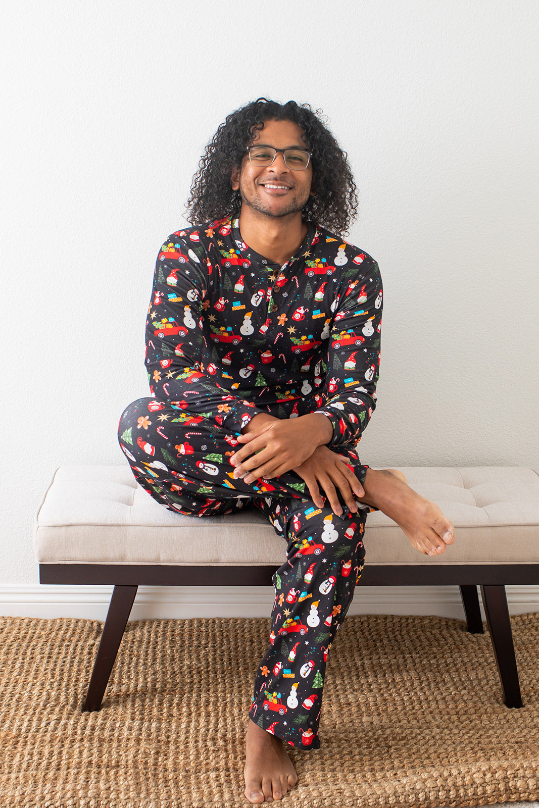 Man wearing colorful pajamas sitting on a bench with a white wall background