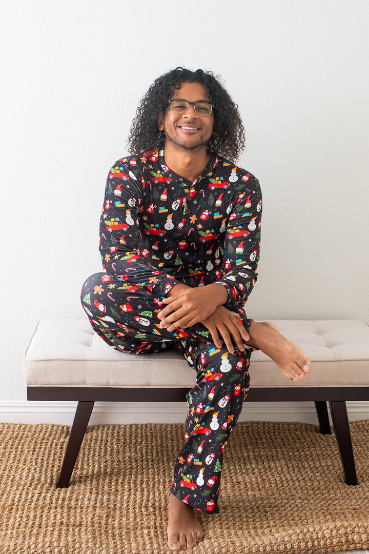 Man wearing colorful pajamas sitting on a bench with a white wall background