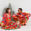 Family in matching red pajamas with Christmas tree in the background