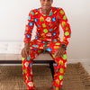 Man wearing a colorful pajama set with a festive pattern sitting on a bench.