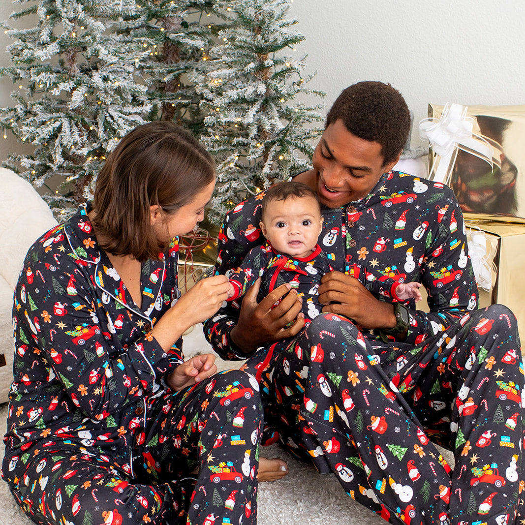 Family in matching pajamas with a baby in a decorated room.