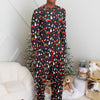 Person wearing festive pajamas standing in a room with a Christmas tree and gifts.