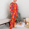 Man wearing a red pajama set with colorful patterns in a room with a Christmas tree and gifts.