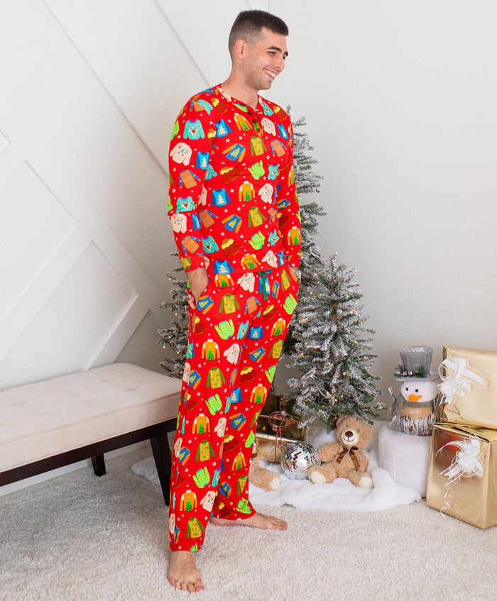 Man wearing a red pajama set with colorful patterns in a room with a Christmas tree and gifts.