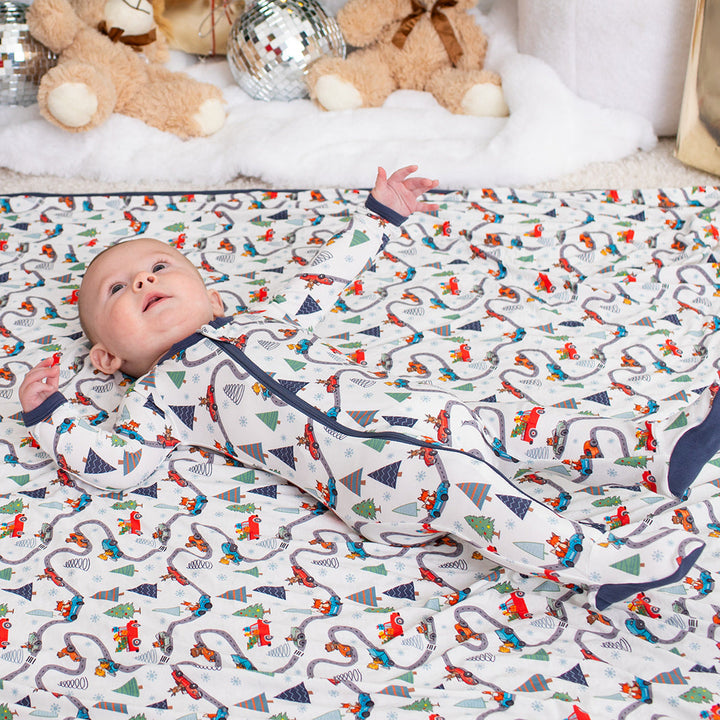 Baby lying on a patterned blanket with Christmas decorations in the background
