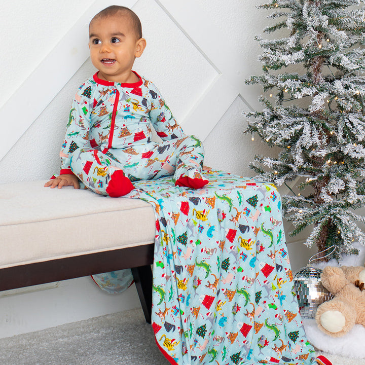 Child in festive pajamas with a Christmas tree and teddy bear in the background
