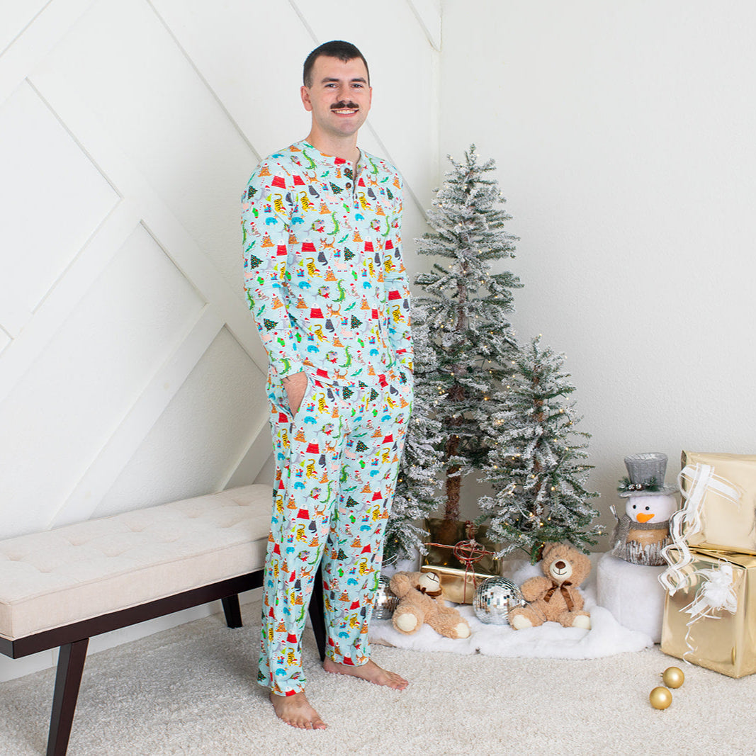 Man wearing a colorful onesie standing in front of a Christmas tree and presents.