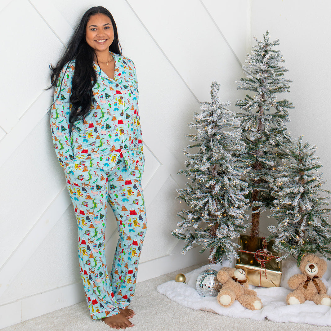 Woman wearing festive pajamas standing next to a decorated Christmas tree with ornaments.