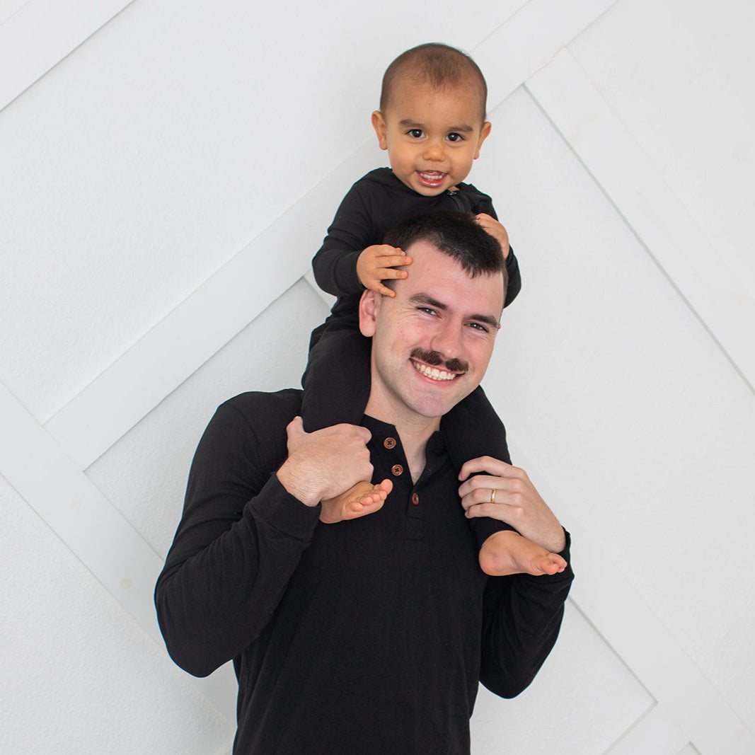 Man with a child on his shoulders against a white geometric background