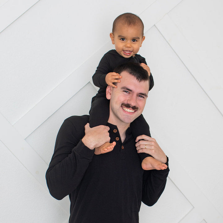 Man with a child on his shoulders against a white geometric background