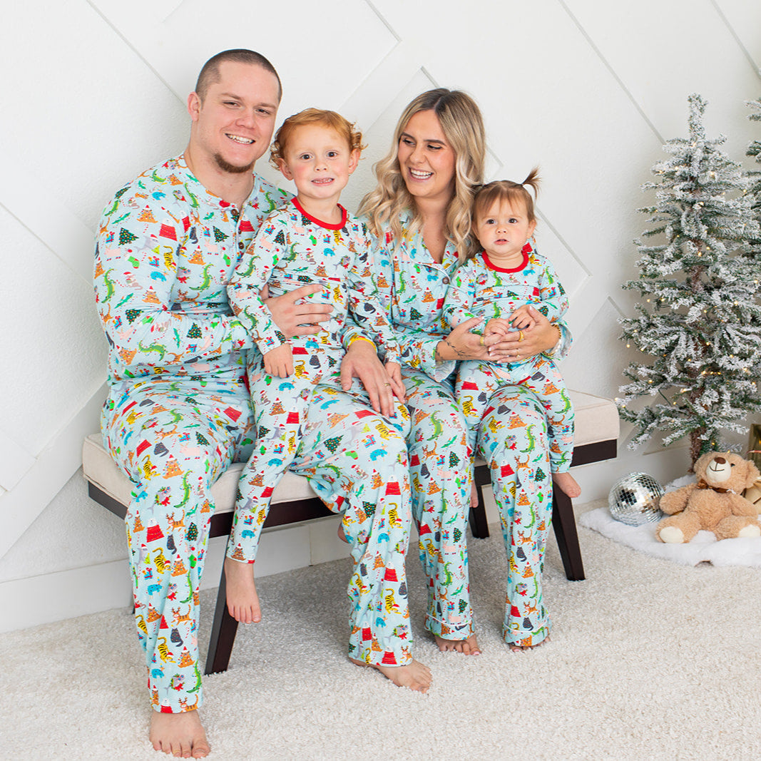 Family of four wearing matching Christmas pajamas in front of a decorated Christmas tree.