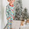 Child wearing Christmas-themed pajamas standing in front of a decorated Christmas tree.