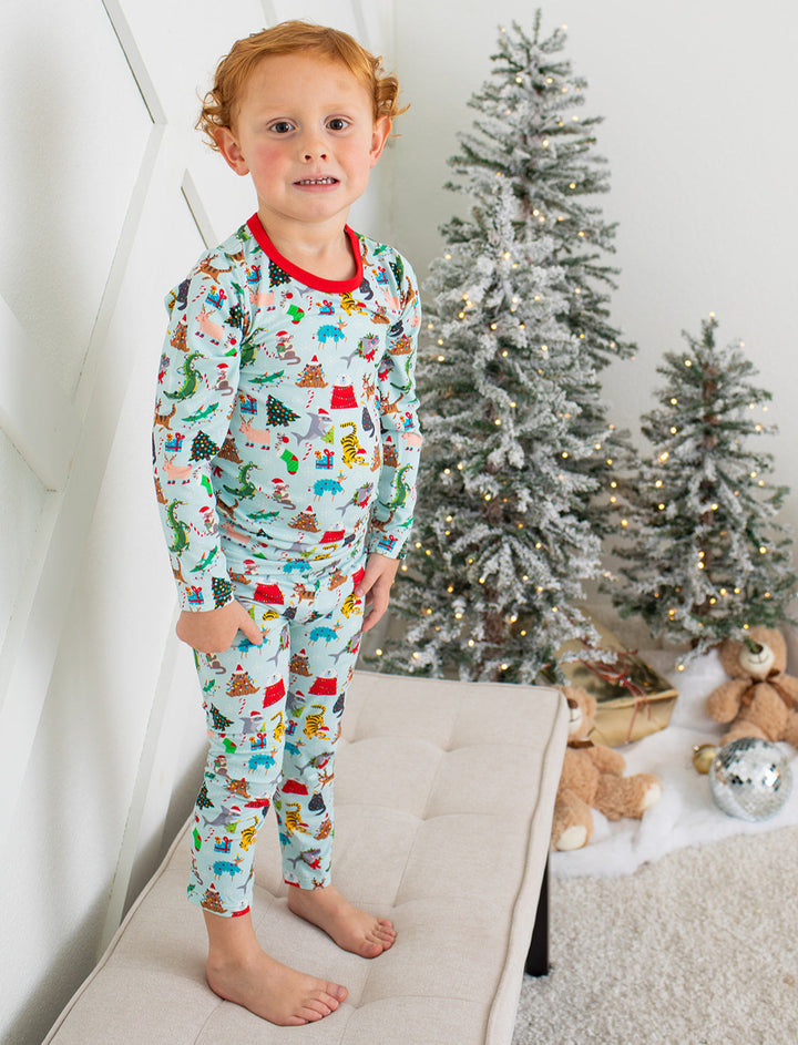 Child wearing Christmas-themed pajamas standing in front of a decorated Christmas tree.