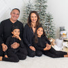 Family of four posing in front of a Christmas tree with decorative items.