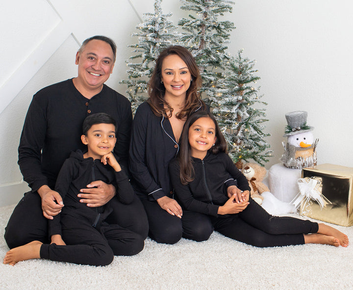 Family of four posing in front of a Christmas tree with decorative items.