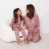 Mother and daughter wearing matching floral pajamas sitting on a white couch.