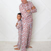 Man and child wearing matching red polka dot pajamas against a white geometric patterned wall.