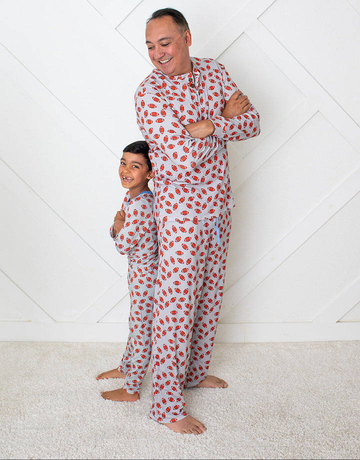 Man and child wearing matching red polka dot pajamas against a white geometric patterned wall.