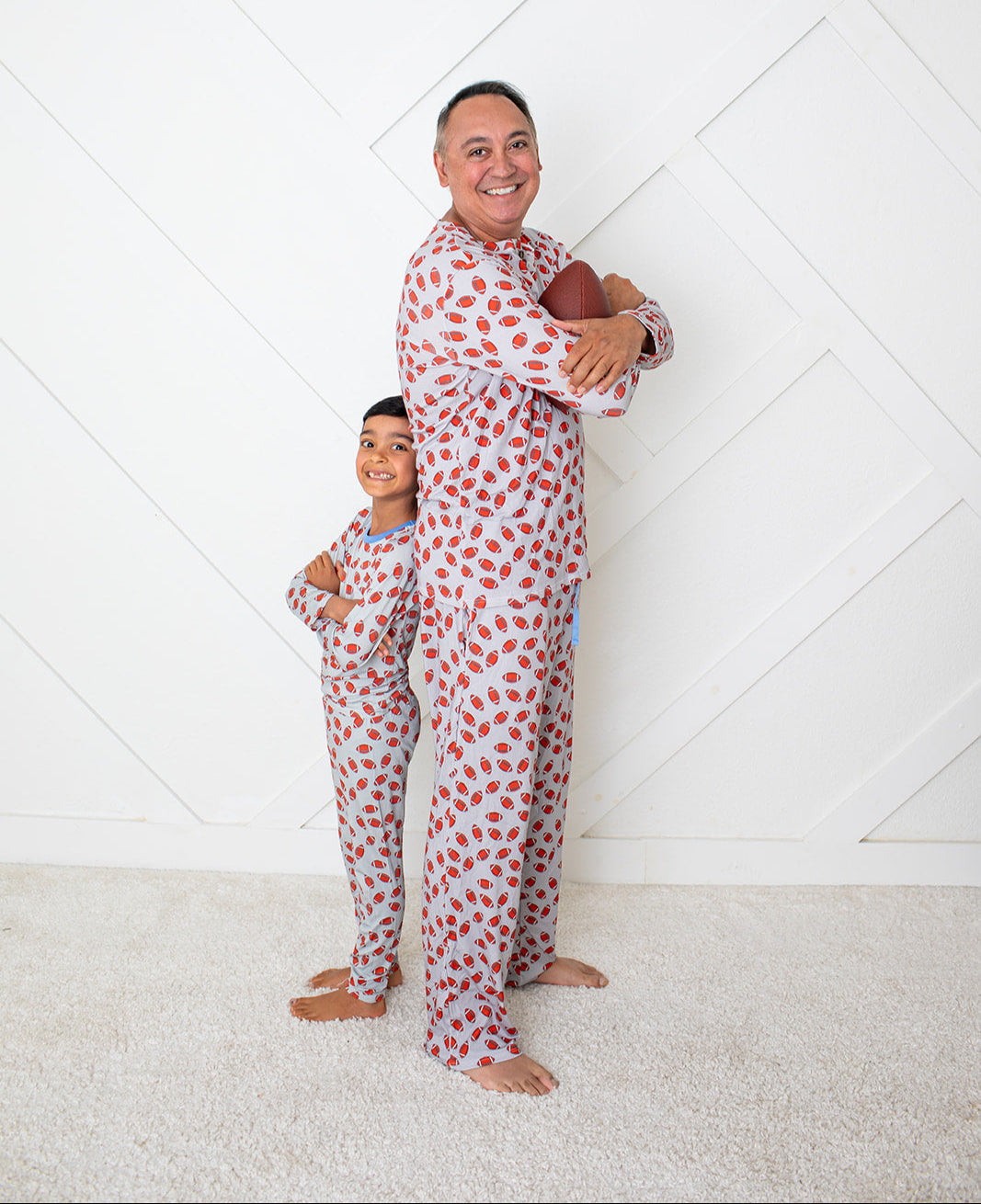 Man and child wearing matching red polka dot pajamas against a white background