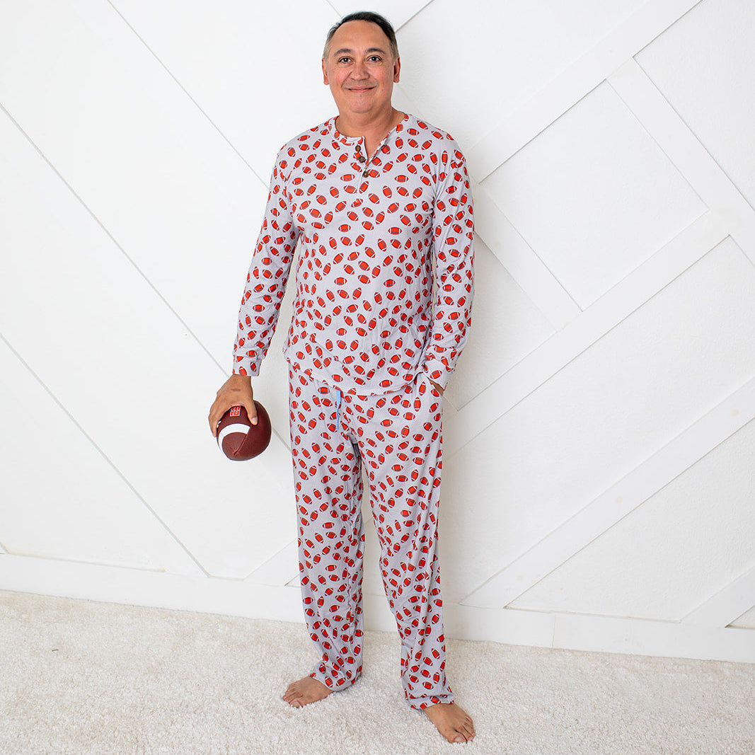 Person wearing a red and white patterned onesie holding a football against a white geometric background