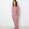 Woman wearing a floral pajama set against a white wall.