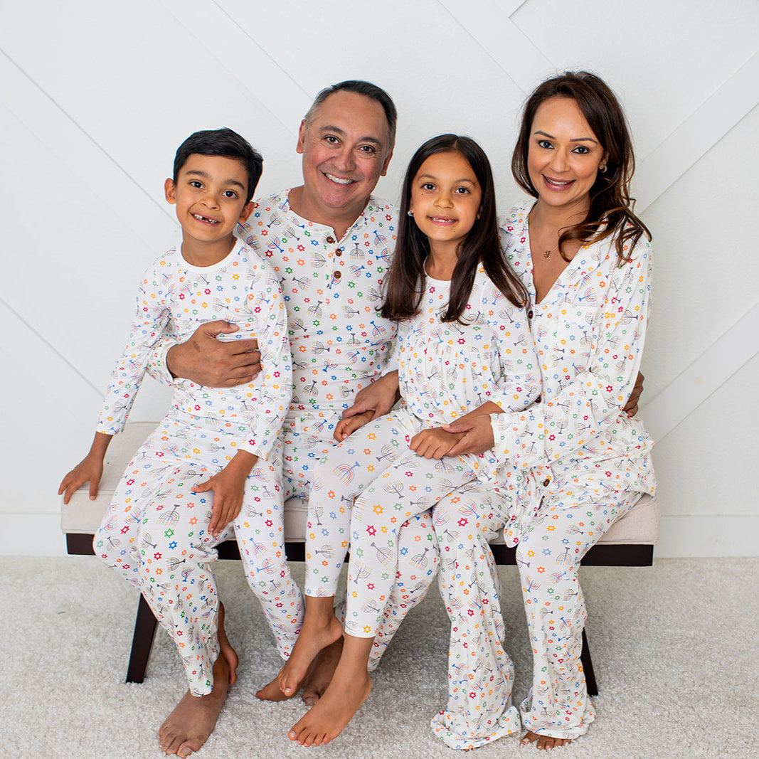 Family of four wearing matching pajamas in a room with a white geometric patterned wall.