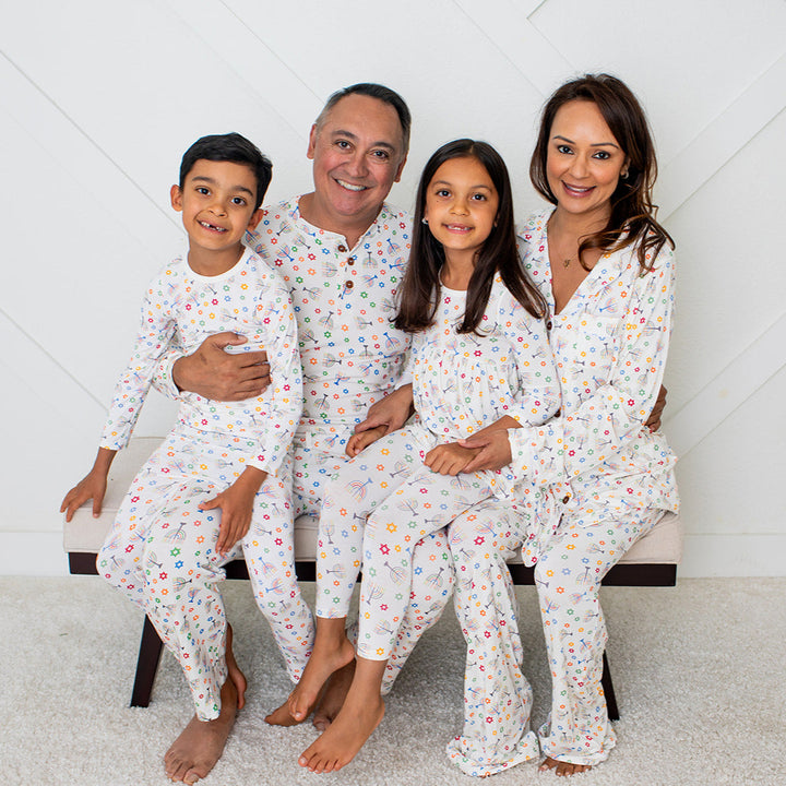 Family of four wearing matching pajamas in a room with a white geometric patterned wall.