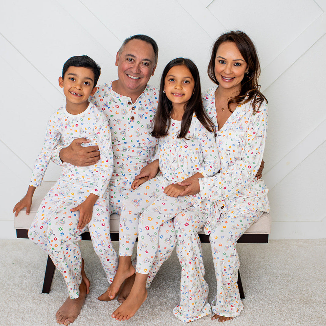 Family of four wearing matching pajamas in a room with a white geometric patterned wall.