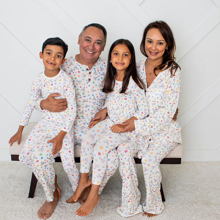 Family of four wearing matching pajamas in a room with a white geometric patterned wall.